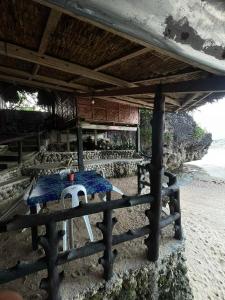 a table sitting under a roof on a beach at Gratum Beach 1 & 2 Resorts Glamping in Dapitan