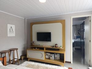 a living room with a tv and a mirror at Hospedagem Doce Lar - Casa Manacá in Teresópolis
