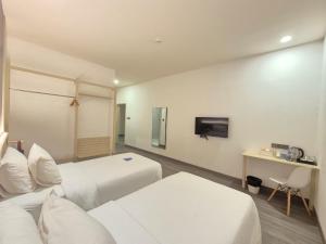 a hotel room with two beds and a television at True Blue Hotel Menteng in Jakarta