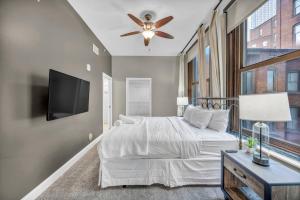 a bedroom with a bed with a ceiling fan and a tv at LUXE Condo Downtown | Security•Gym•Parking in Cleveland