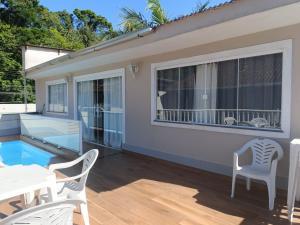 a patio with a table and chairs and a pool at Hospedagem Doce Lar - Casa Manacá in Teresópolis