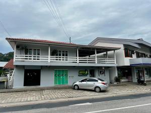 a white house with a car parked in front of it at Casa com churrasqueira e ar para até 8 pessoas in Guabiruba