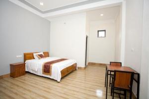 a bedroom with a bed and a desk and a table at Linda Home in Phường Chày