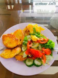 a white plate of food with a salad and potatoes at Linda Home in Phường Chày