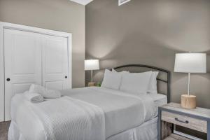 a white bedroom with a large bed and a table at Central Downtown Loft | Parking•Gym•Security in Cleveland