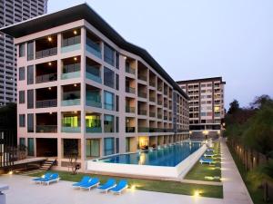 a large building with a swimming pool and blue chairs at Fancy Beachfront Condominium in North Pattaya
