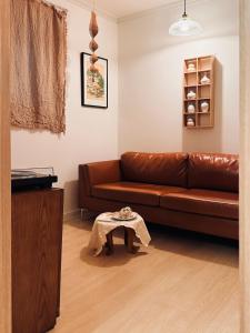 a brown leather couch in a living room with a table at JAJA Haenggung, SuwonㅣNext to Hwaseong FortressㅣCozy Korean VibeㅣComfortable & Well-keptㅣUp to 8 guestsㅣFree ParkingㅣLoved by many guests in Suwon