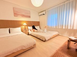 a girl is laying on two beds in a room at JAJA Haenggung, SuwonㅣNext to Hwaseong FortressㅣCozy Korean VibeㅣComfortable & Well-keptㅣUp to 8 guestsㅣFree ParkingㅣLoved by many guests in Suwon