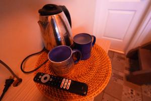 a table with a coffee pot and two cups and a remote control at Serenity Busay Room 6 in Cebu City
