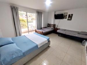 a bedroom with two beds and a large window at Hotel Taganga Plaza Santa Marta in Taganga