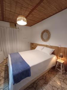 a bedroom with a large white bed and a chandelier at Pousada Villa Grega de Piri in Pirenópolis