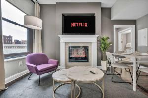 a living room with a fireplace with a tv above it at Upscale Downtown Loft | Parking • Gym in Cleveland