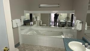 a person taking a picture of a bathroom with a tub at Burntwood Hotel and Restaurant in Thompson