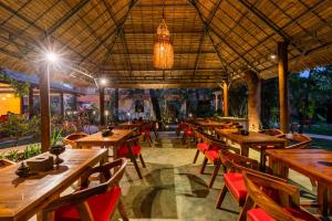 a restaurant with wooden tables and chairs and a chandelier at Kampung Kamboja in Phum Pobos