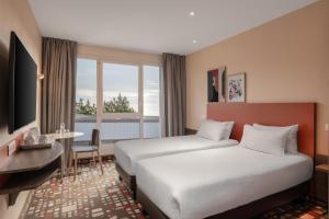 a hotel room with two beds and a table at Spark by Hilton Lyon Eurexpo in Genas +81 photos