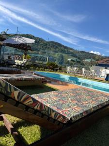 a swimming pool with two lounge chairs and a table at Chácara Bora Bora in São Bento do Sapucaí