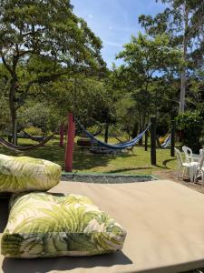 a bed with pillows in a park with a hammock at Chácara Bora Bora in São Bento do Sapucaí
