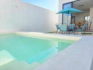 a swimming pool with chairs and a blue umbrella at Casa Havana Mid in Mérida