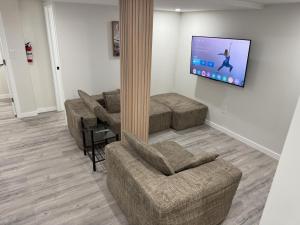 a living room with couches and a flat screen tv at Urban Haven Suite in Winnipeg