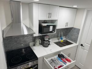 a kitchen with white cabinets and a black microwave at Urban Haven Suite in Winnipeg