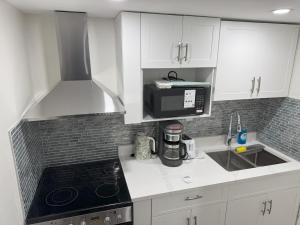 a kitchen with white cabinets and a black stove top oven at Urban Haven Suite in Winnipeg +9 photos