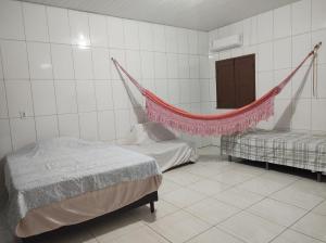 a bedroom with two beds and a hammock in it at Rosa cheirosa in Barreirinhas