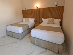 two beds in a hotel room with marble floors at Hotel JVD Inn - Tonalá Centro GDL in Guadalajara