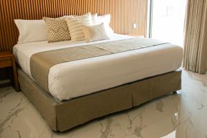 a bed with white sheets and pillows in a room at Hotel JVD Inn - Tonalá Centro GDL in Guadalajara