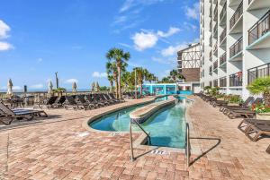a swimming pool at a resort with lounge chairs at Last Chance Summer, Oceanfront Pools and Beach in Myrtle Beach