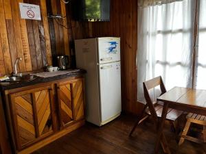 a kitchen with a white refrigerator and a table at Cabañas El Macuco in Dos de Mayo