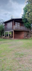 a large wooden house with a porch on a field at Cabañas El Macuco in Dos de Mayo
