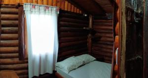 a small bed in a room with a window at Cabañas El Macuco in Dos de Mayo