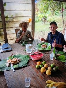 two men sitting at a wooden table with food on it at Roots Casa Rústica in Valle Hornito