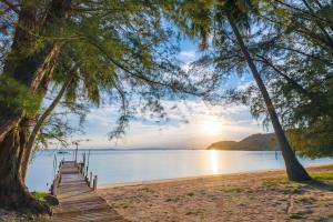 a wooden dock on a beach with a sunset at Twinbeach Sanctuary in Mersing