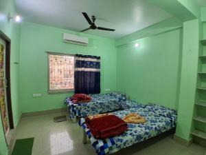 two beds in a room with green walls at Bhakta Bhawan in mayapur