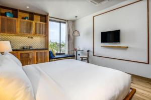 a bedroom with a white bed and a television at Riverside Seahorse Danang Hotel in Danang