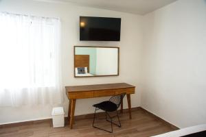 a desk in a room with a mirror and a chair at Hotel La Siesta, Gomez Palacio in Gómez Palacio