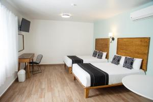 a hotel room with two beds and a desk at Hotel La Siesta, Gomez Palacio in Gómez Palacio