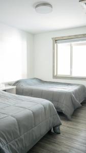 two beds in a white room with a window at Elk Horn Cabin Rental in Valemount