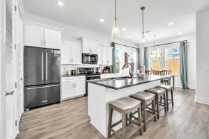 a kitchen with white cabinets and a large island with bar stools at Emerald Escape in Destin, Miramar Beach! 4BR, 4BA, 1st Floor Bedroom, Sleeps up to 14, Golf Cart Included, Pool, Pet Friendly, Private Deeded Beach Access & Gated Community! in Destin