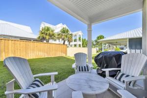 a patio with chairs and a table and a fence at Emerald Escape in Destin, Miramar Beach! 4BR, 4BA, 1st Floor Bedroom, Sleeps up to 14, Golf Cart Included, Pool, Pet Friendly, Private Deeded Beach Access & Gated Community! in Destin