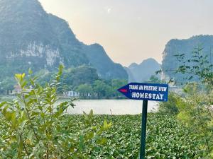 a blue sign in front of a river with mountains at Trang An Pristine View Homestay in Ninh Binh