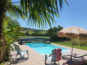 a swimming pool with two chairs and a umbrella at Pause Campagne - Chambres d'Hôtes in Pouy-de-Touges