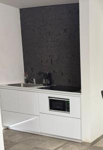a white kitchen with a sink and a microwave at Punta Lobos in Reynosa