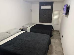 a small room with two beds and a television at Punta Lobos in Reynosa