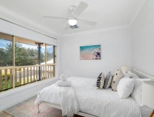 a white bedroom with a bed and a balcony at Beach Street Stay in Harrington +7 photos