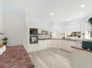 a large white kitchen with white cabinets and windows at Beach Street Stay in Harrington