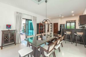 a kitchen and dining room with a glass table and chairs at Tranquil 4BR Garden Pool Oasis - Layan Beach in Laguna Phuket