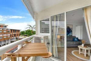 a balcony with a wooden table and a couch at Northshore Palms Apartment in Cairns North