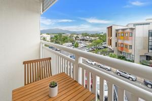a balcony with a wooden table and a view of a city at Northshore Palms Apartment in Cairns North